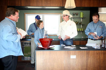 Photo of four men and one woman standing inside the kitchen of a home. 