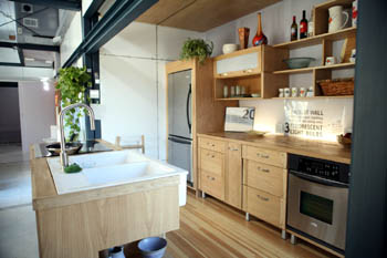 Photo of a galley-style kitchen with double white sinks and stainless steel appliances.