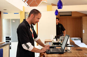 Photo of a young man in a black T-shirt working on a laptop computer.