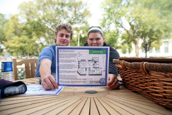 Photo of a young man and woman holding and displaying a brochure