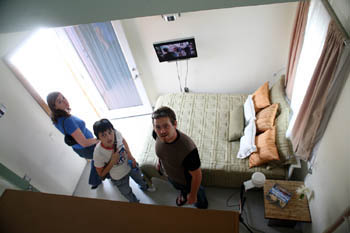Photo of three people standing in a bedroom. The shot is taken from on high.
