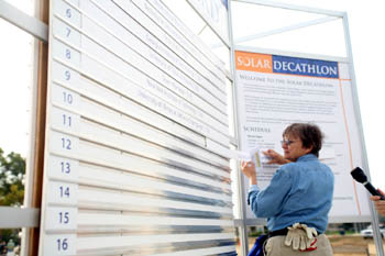 Photo of a woman adjusting a large sign.