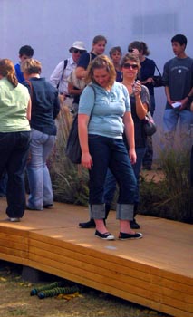 Photo of a women standing on the entry ramp to a solar house looking down at two stuffed socks sticking out from under the ramp.