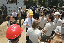 Photo of Secretary of Energy Samuel Bodman standing in front of the Habitat for Humanity house, wearing a hard hat and speaking to the volunteers.