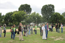 Photo of approximately 25 members of Germany standing and chatting in a grassy area on the National Mall.