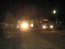 Photo of a diesel truck driving through a finish line type at night. Bright lights, people in safety vests, and the U.S. Capitol can be seen in the background.