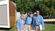 Photo of one woman and two men wearing denim shirts and standing next to Team California's house.