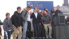 Photo of a group of young people standing on a raised platform with a Solar Decathlon sign as a backdrop.