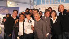 Photo of a group of people smiling. One holds a silver trophy.