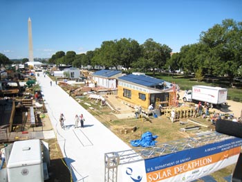 Aerial photo of two rows of houses under construction. In the middle is a long walkway. In the background is the Washington Monument.