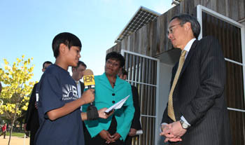 Photo of a young person holding a microphone and talking with Secretary Chu. A woman looks on in the background.