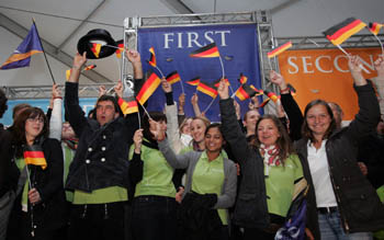 Photo of a group of students waving German flags and cheering in front of a first-place award banner.