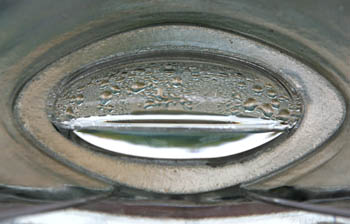 Photo of an abstract silver shape with water droplets on top.