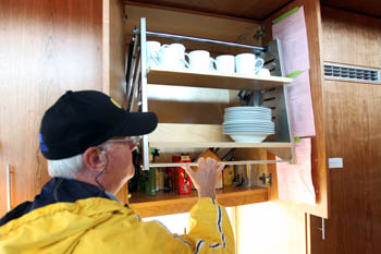 Photo of a man pulling a set of extendable shelves from a kitchen cabinet to a lower level.