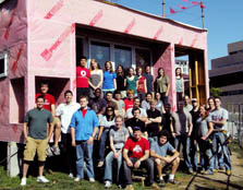 Photo of a group of approximately 35 Ohio State University students standing and sitting in front of their Solar Decathlon house, which is still under construction.