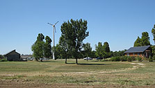 Photo of the 2005 and 2002 Crowder College solar houses on either side of a wind turbine on the school's campus.