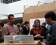 Photo of students discussing architectural model of a house.