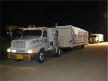 Photo of tractor-trailer trucks carrying house sections.