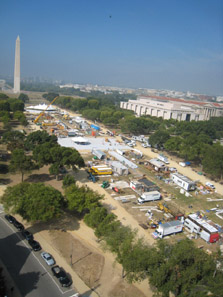 An aerial view of the Solar Decathlon includes 17 partially constructed solar houses, two large tents, a large crane, and a lot of construction clutter. The Washington Monument is visible in the background.