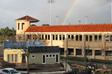 Photo of Santa Clara University's Ripple House on campus with a rainbow in the sky behind it.